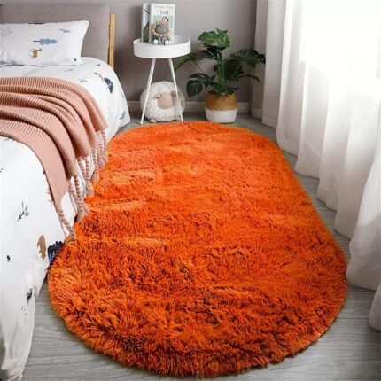 An orange oval fluffy area rug with a high pile texture, perfect for a living room or bedroom floor.
